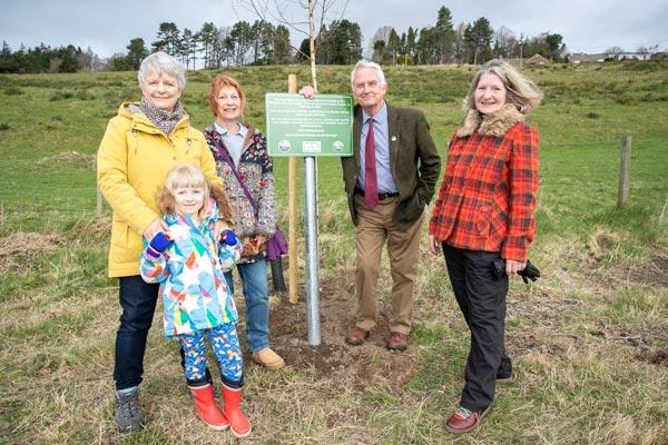 Councillor Glen Sanderson and Tree wardens standing around a tree and a plaque.