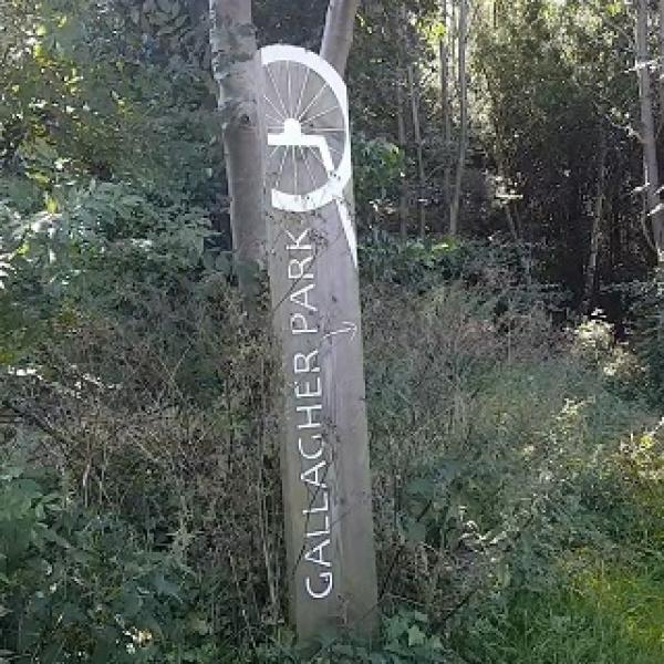 A wooden post with "Gallagher Park" carved into the side