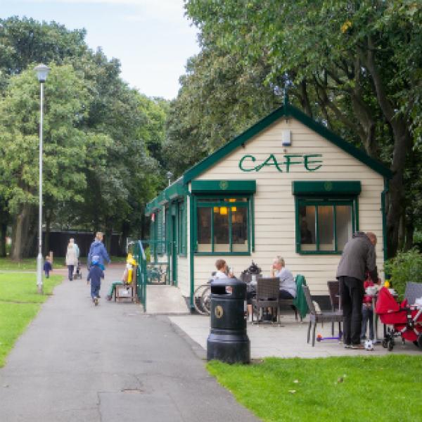 A small white building with cafe on the side. There's small seating area outside