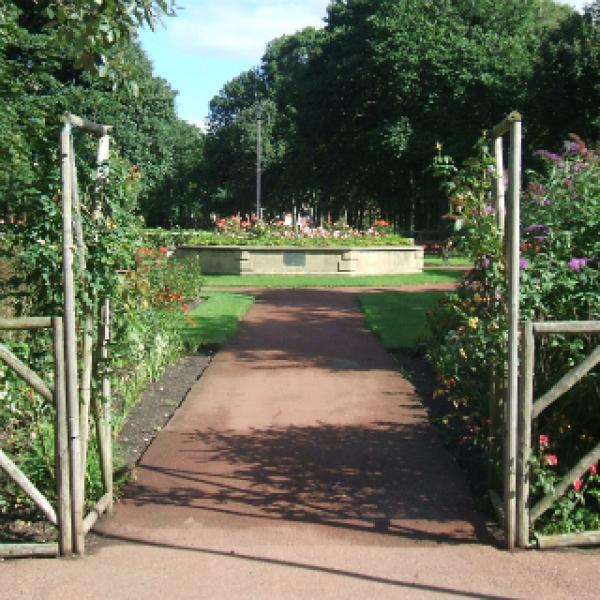 Two wooden fences open up to make an entrance for the flower garden with a red path.